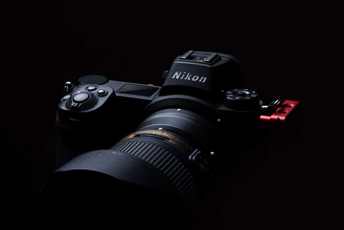 A dark photo with a close up of a Nikon camera and lens