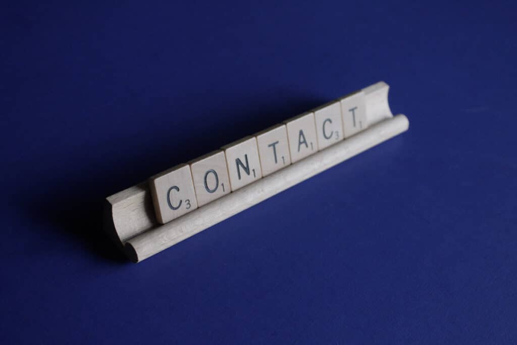 A blue board with scrabble tiles spelling contact