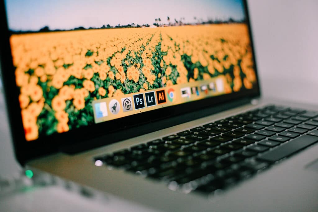 A laptop showing adobe programs. The screen has flowers on it