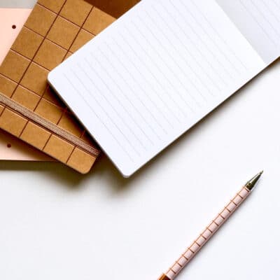 Three notebooks and a pen on a table - square