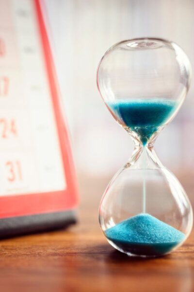 An hour glass with blue sand and a calendar