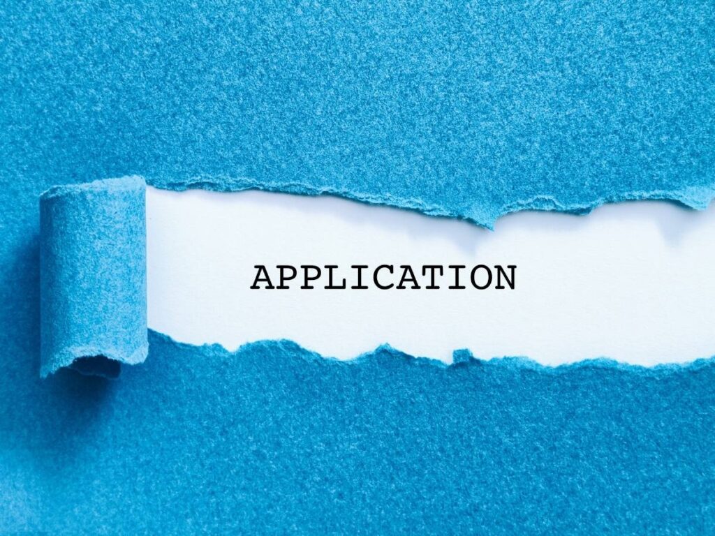 blue paper ripped to expose the word application