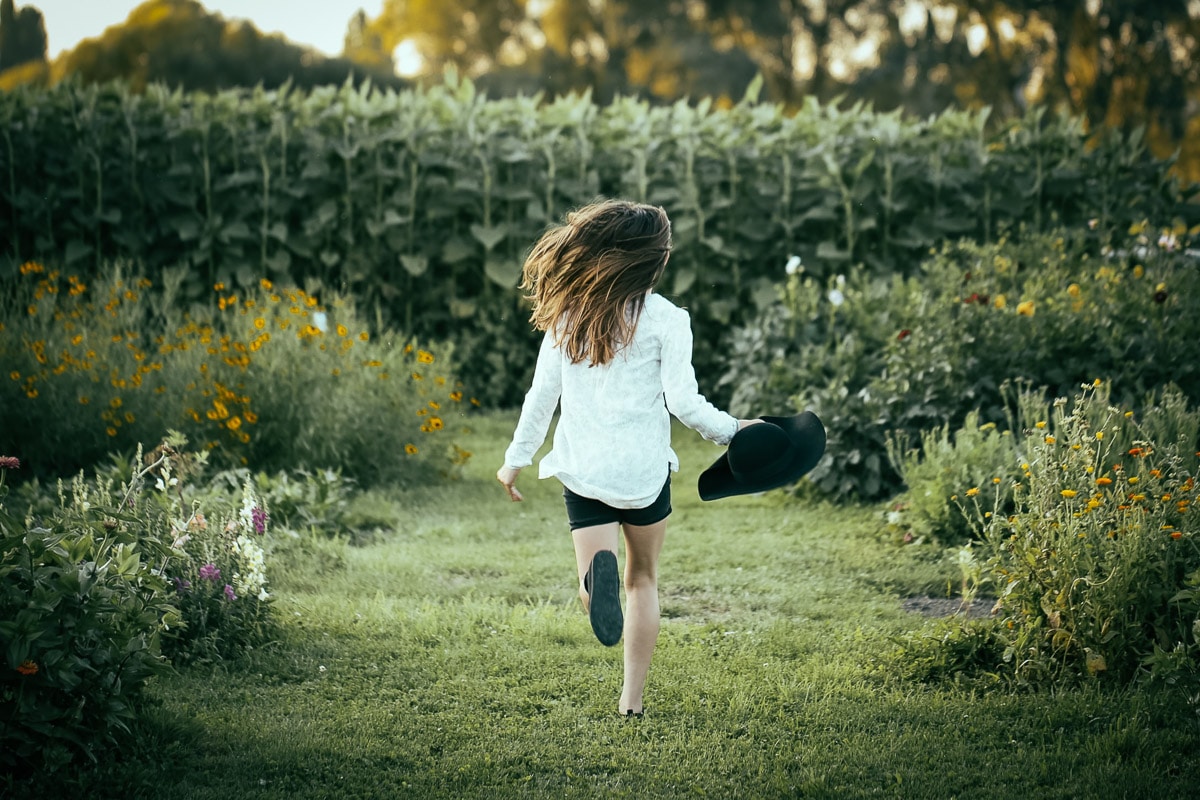 A female running away from the camera towards corn stalks