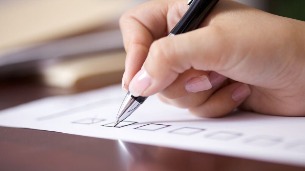 woman's hand holding pen and checking boxes on a piece of paper