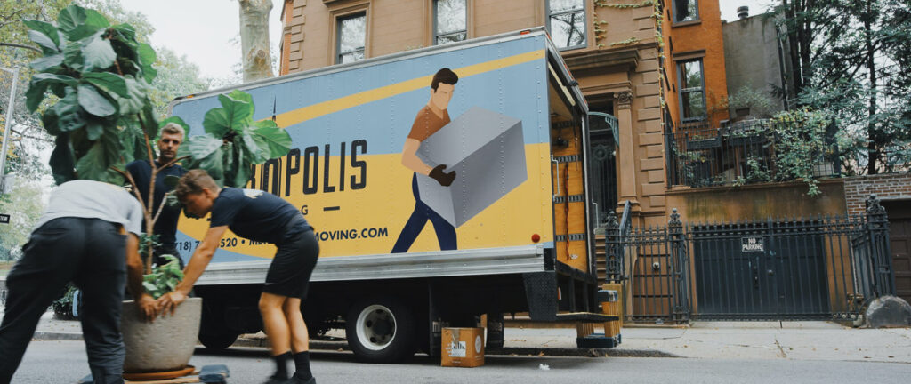 a moving truck with people picking up a big plant