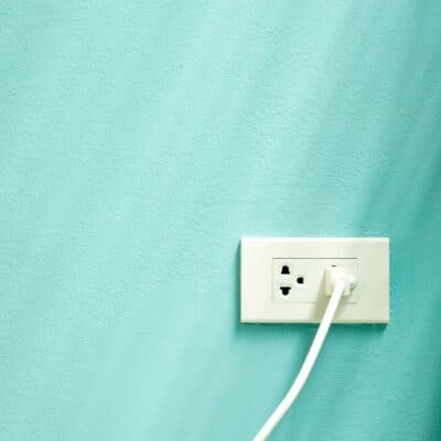 A blue-green wall with a white plug in a white socket