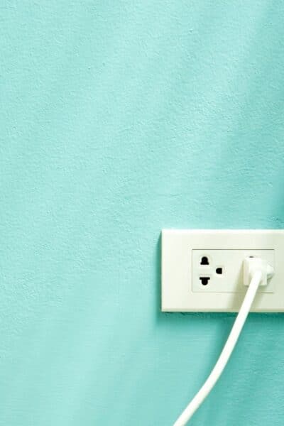 A blue-green wall with a white plug in a white socket