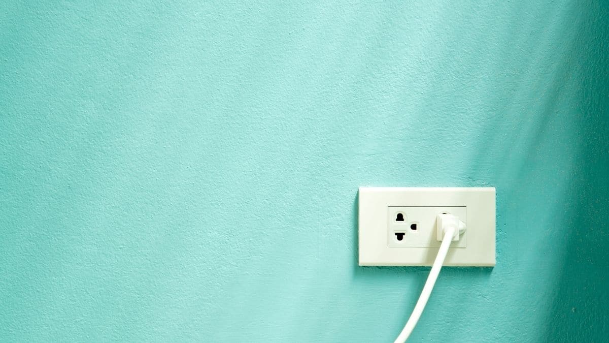 A teal wall with a plug in the white socket